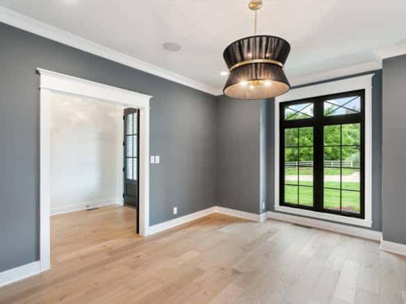 Spacious room featuring gray walls, a large window, and light wood flooring, ideal for a comfortable.