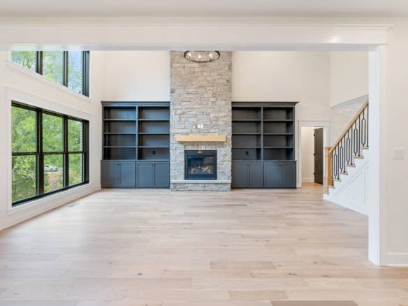 Spacious living room featuring a stone fireplace and custom built-in shelves.
