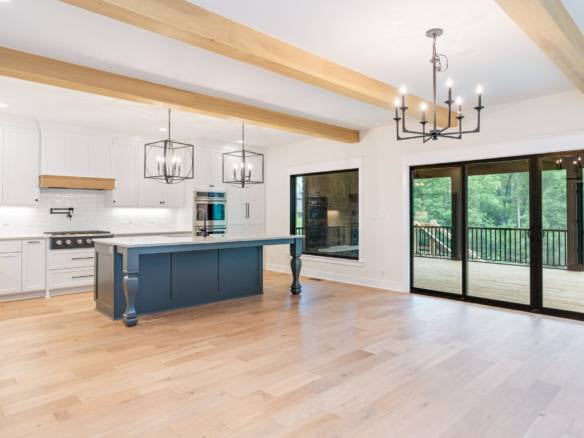 Modern kitchen with white cabinets, a large island, and ample natural light from sliding glass doors.
