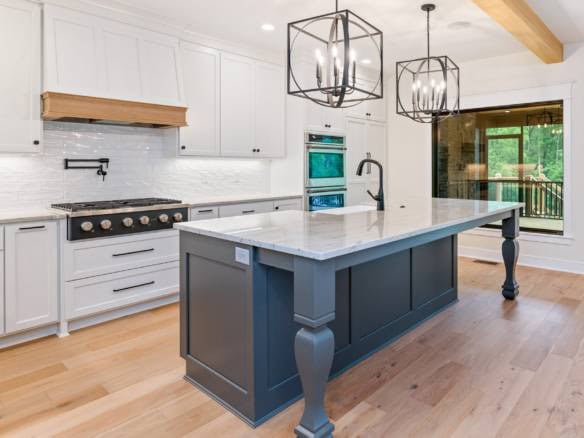 Bright modern kitchen with white cabinets, blue island, and large window.
