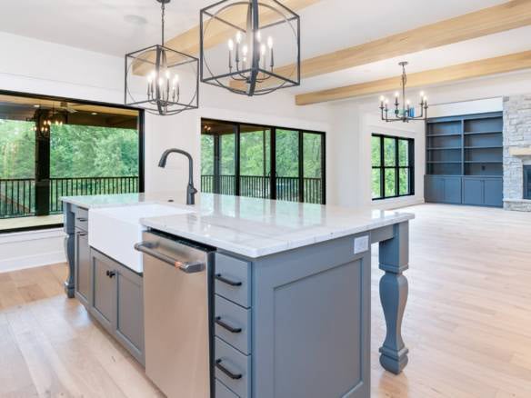 Bright modern kitchen with large windows, island, and contemporary lighting fixtures.