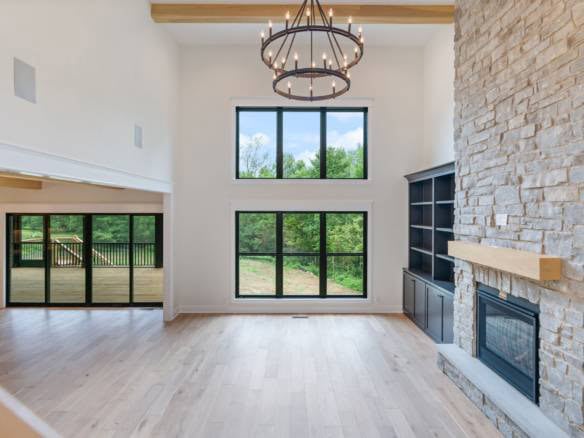 Spacious living room featuring large windows, a stone fireplace, and high ceilings, showcasing custo.