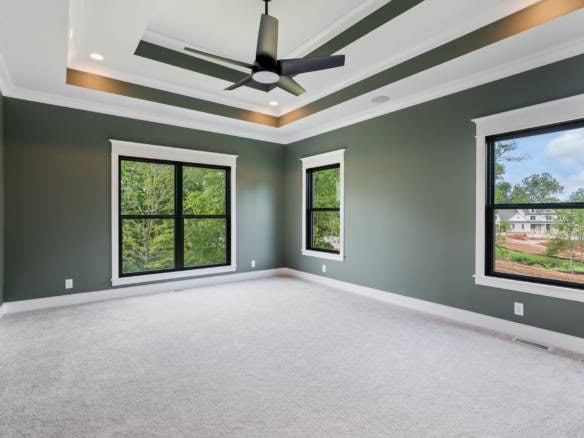 Modern living room featuring three large windows, a ceiling fan, and neutral wall colors for a spaci.
