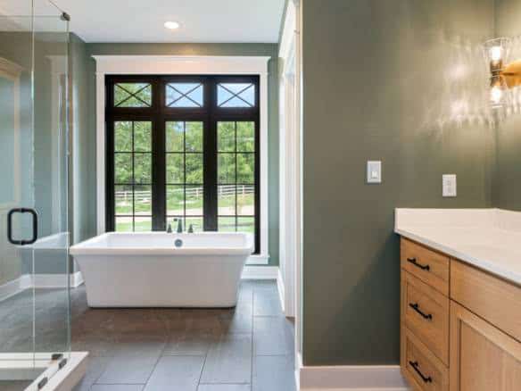 Modern bathroom with freestanding tub and glass shower, featuring green walls and natural light at 1.