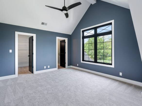 Modern blue bedroom with large window and vaulted ceiling.