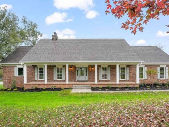 Beautiful brick ranch house with front porch and lush lawn.