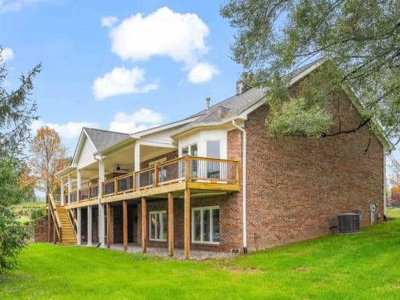 Back view of a newly built brick house with a spacious wooden deck and green lawn.