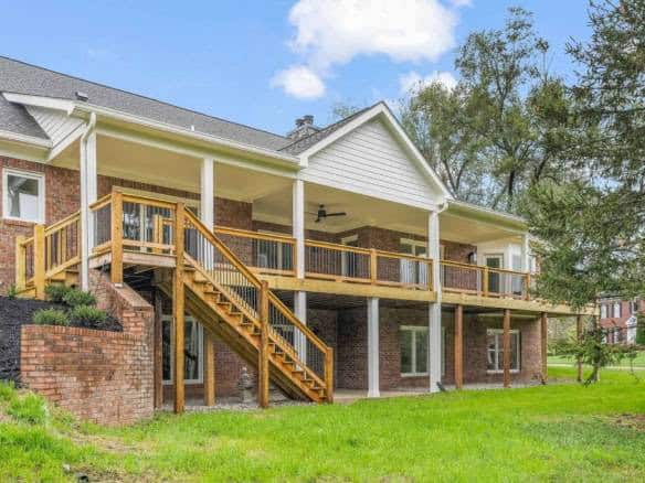 Beautiful brick house with large elevated wooden deck and stairs, perfect for outdoor living and ent.