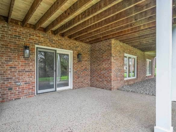 Outdoor brick patio with sliding doors and covered roof for outdoor living.