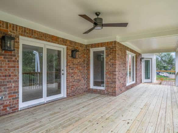 Modern brick porch featuring sliding glass doors and a ceiling fan for outdoor comfort.