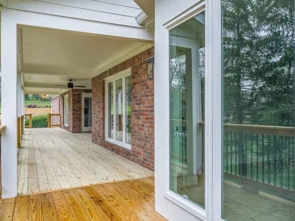 Porch with brick walls, large windows, and wooden flooring at 11714 Paramont Way.