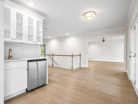 Spacious open-concept living area with white walls, hardwood floors, and large windows.