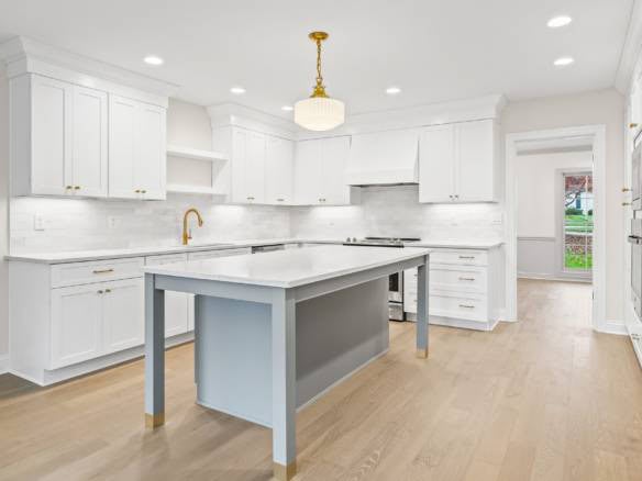 Modern white kitchen with island, gold fixtures, and ample storage space.