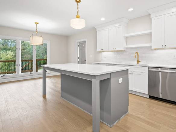 Bright, open-concept kitchen featuring white cabinetry, a large island, and ample natural light.