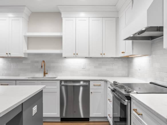 Bright, modern kitchen featuring white cabinets, stainless steel stove, and gold hardware.