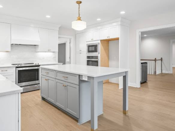Kitchen with white cabinetry and central island for cooking and dining.