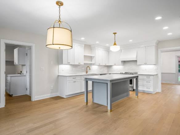 Kitchen with white cabinets, central island, and gold fixtures.