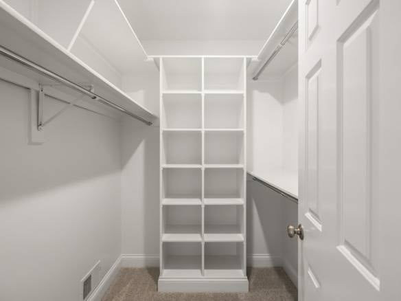 Closet storage with shelves and hanging rods in a modern walk-in closet.