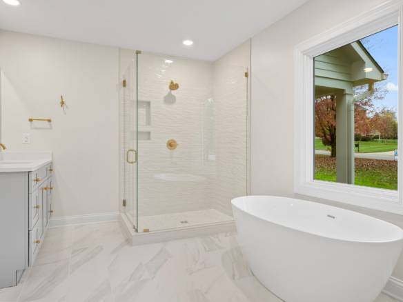 Bright bathroom featuring a spacious walk-in shower and elegant freestanding bathtub under a large w.