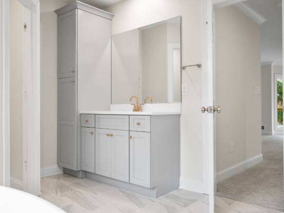 Modern bathroom vanity with light gray cabinetry and gold fixtures.