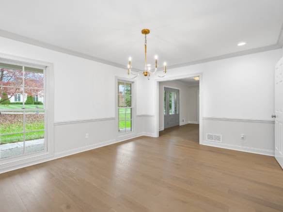 Spacious living room with large windows, white walls, and hardwood flooring, showcasing a bright and.