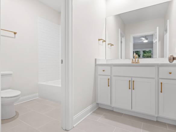 Bathroom with white cabinets, gold hardware, and a large mirror.