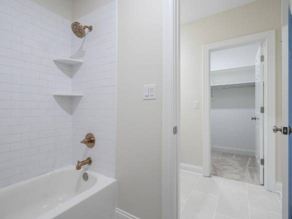 Bathroom with bathtub, shower, and built-in shelves at 11714 Paramont Way.