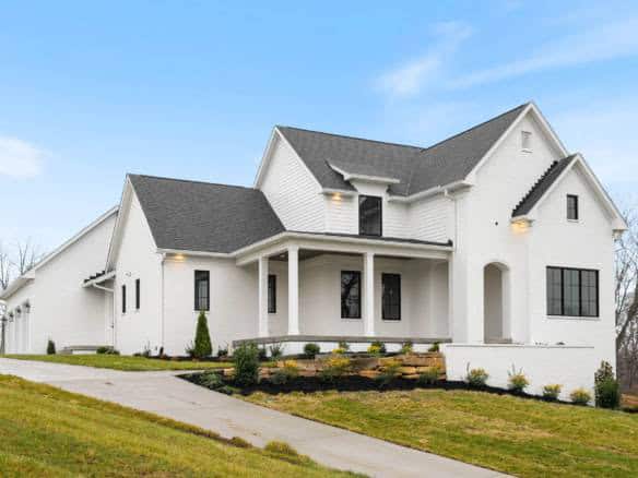 White house with front porch, black window frames, and landscaped yard at 3979 Hidden Falls Drive.