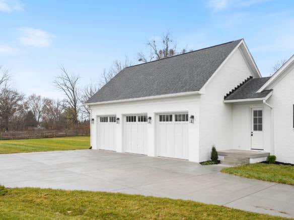 Garage with three white doors and black hardware, set against a clear blue sky.