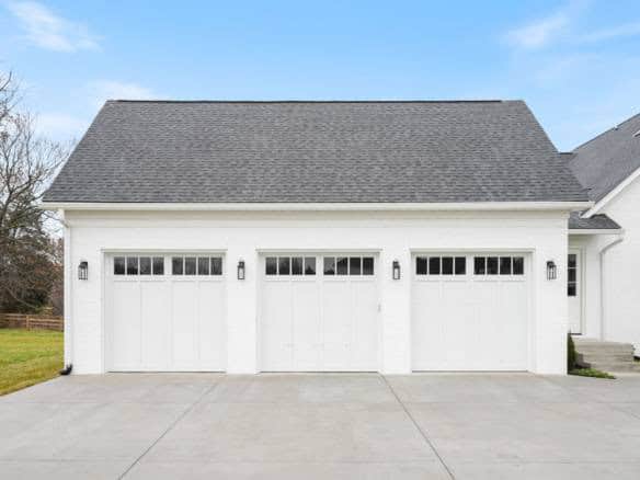 White garage with four doors and black hardware, part of a new residential construction.