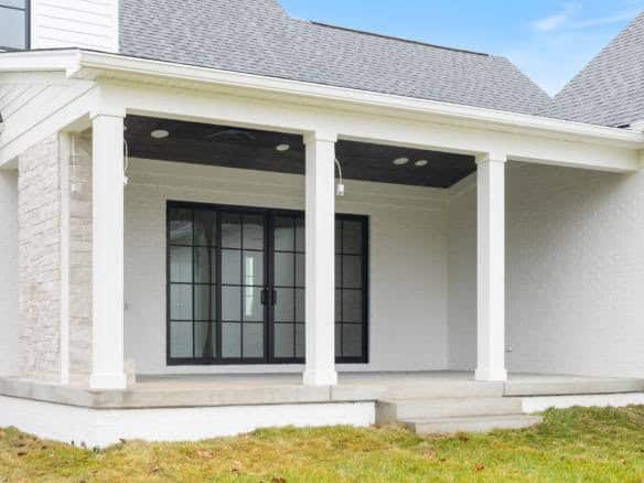 Covered patio with black-framed glass doors and white columns at 3979 Hidden Falls Drive.