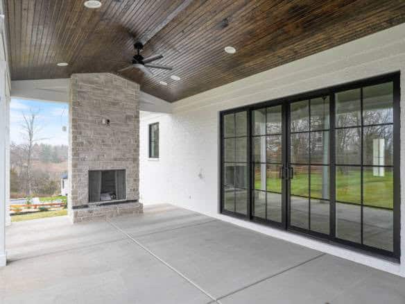Screened porch with fireplace and expansive glass doors for outdoor living.