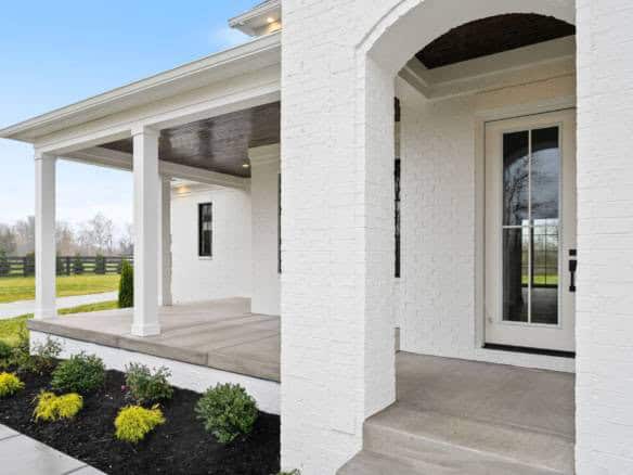 Beautiful white brick porch with a covered entryway and front door at 3979 Hidden Falls Drive.