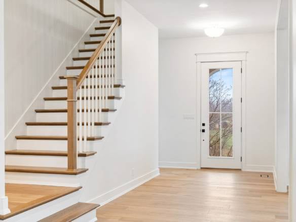 Entryway with white walls and wooden staircase.