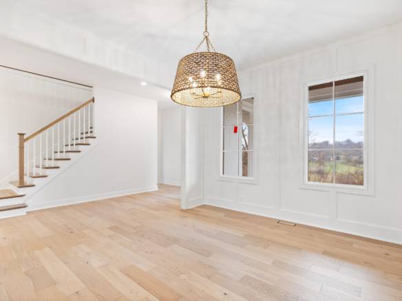 Interior view of a bright, spacious living room with large windows and a stylish chandelier.
