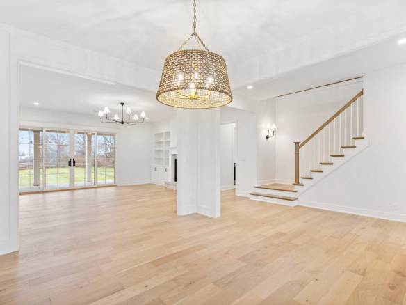 Spacious living room with hardwood floors, large windows, and elegant lighting fixtures.