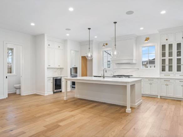 Spacious, bright kitchen featuring white cabinetry, island, and hardwood floors at 3979 Hidden Falls.