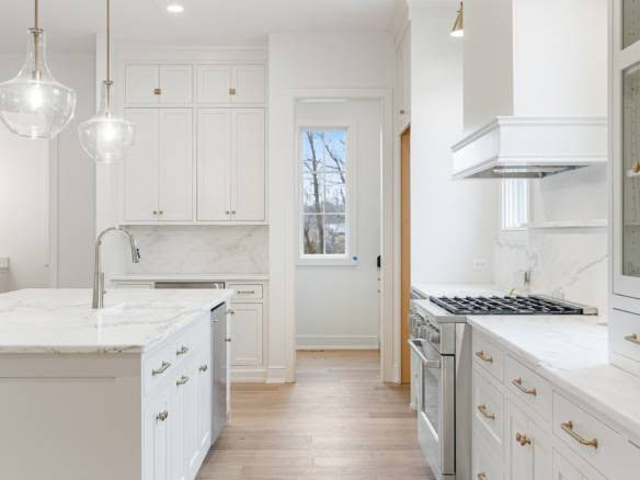 White kitchen with cabinetry, marble countertops, and large window.