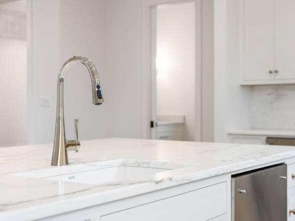 Modern kitchen with marble countertops, stainless steel sink, and white cabinetry.
