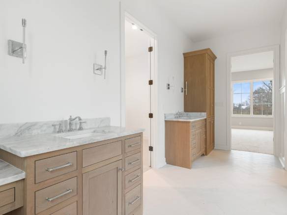 Modern bathroom featuring dual vanities, marble countertops, and a large window with natural light.