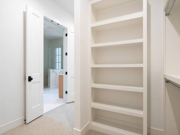 Walk-in closet with white shelving and storage area in a new home.