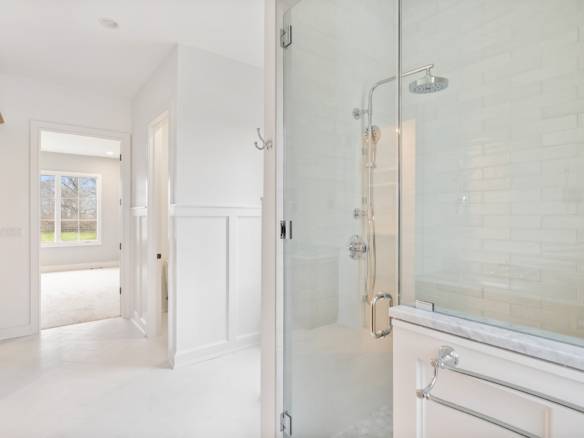 Modern bathroom with glass shower enclosure and white interior design.