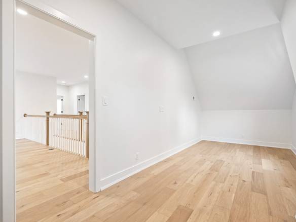 Attic room with white walls and light wood flooring, perfect for a home office or storage.