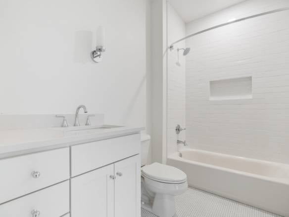 Bathroom renovation with white cabinetry, bathtub, and modern fixtures.