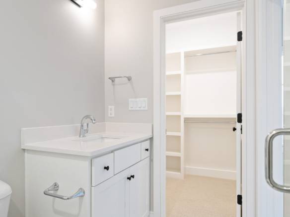 Laundry room with white cabinets and a walk-in closet in a new home.