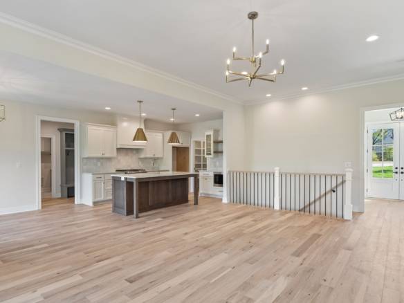 Spacious open-concept kitchen and living space with hardwood floors, stylish lighting, and large win.