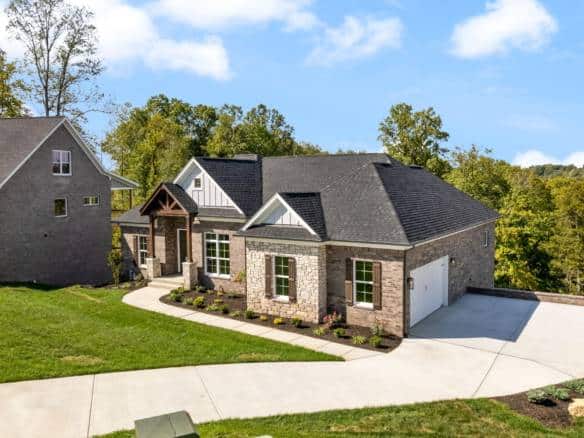 Beautiful new construction home with stone and siding exterior, landscaped yard, and attached garage.