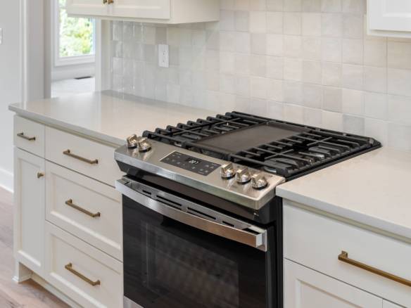Kitchen stove with white cabinetry and tiled backsplash.