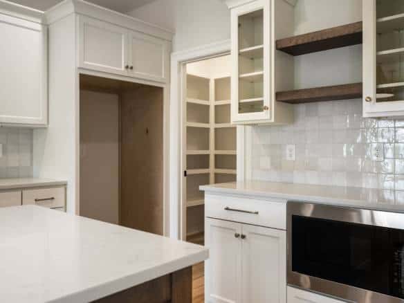 Bright kitchen featuring white cabinetry and open wooden shelves.