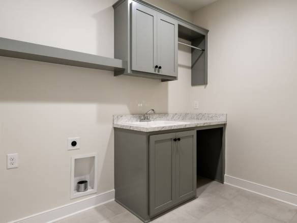 Laundry room with gray cabinets and marble countertop in a residential home.